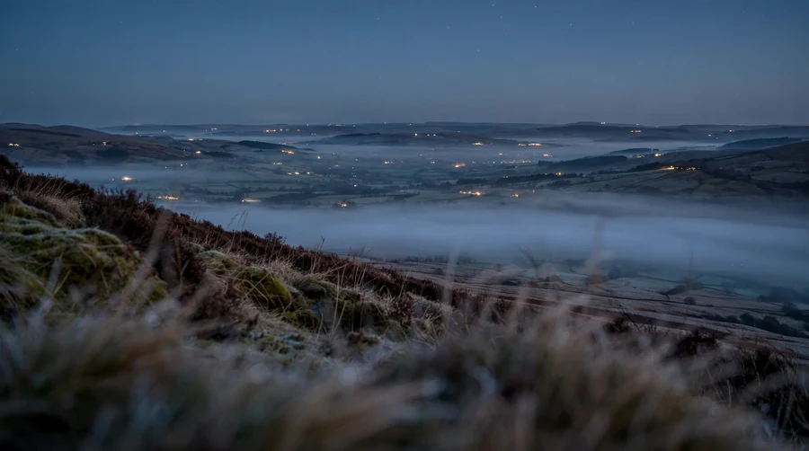 A wide cold valley at night with mist in the bottom, the conditions in which sound carries much further than expected